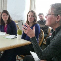 A woman speaks to a group about the Genuine Progress Idicator