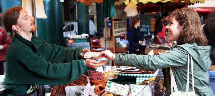 A man sells baked goods to a woman